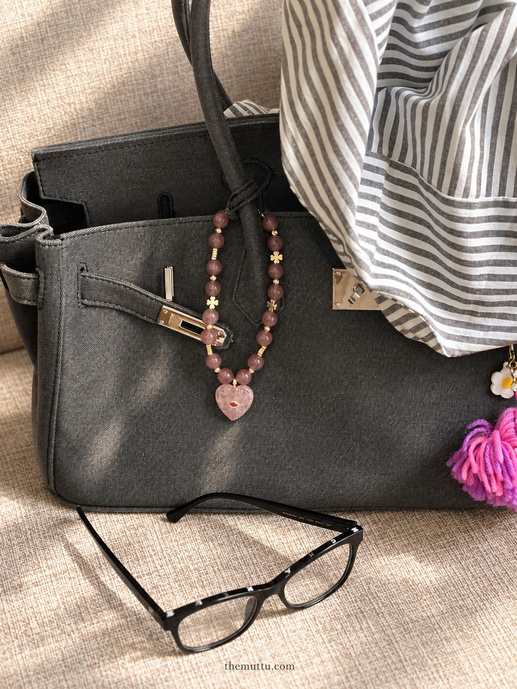 Pink strawberry quartz heart crystal charm hanging as a luxury accessory on a dark handbag – Muttu

