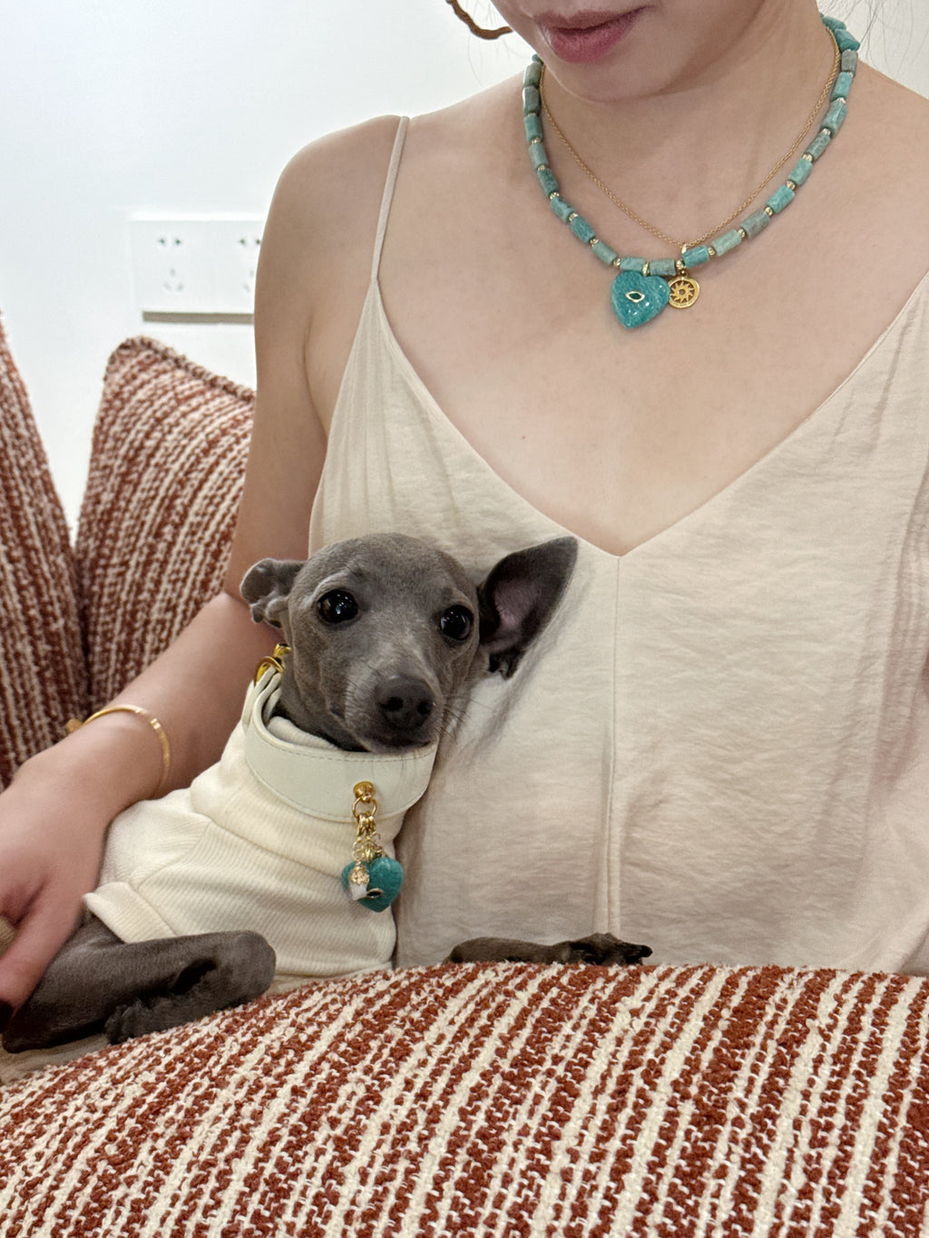 Owner and Italian Greyhound cuddling on sofa wearing matching green amazonite heart crystal necklace and collar charm – Muttu
