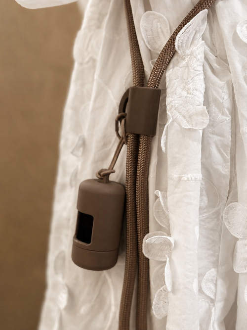 Close-up detail of the brown Muttu poop bag dispenser securely attached to the hands-free crossbody dog leash.