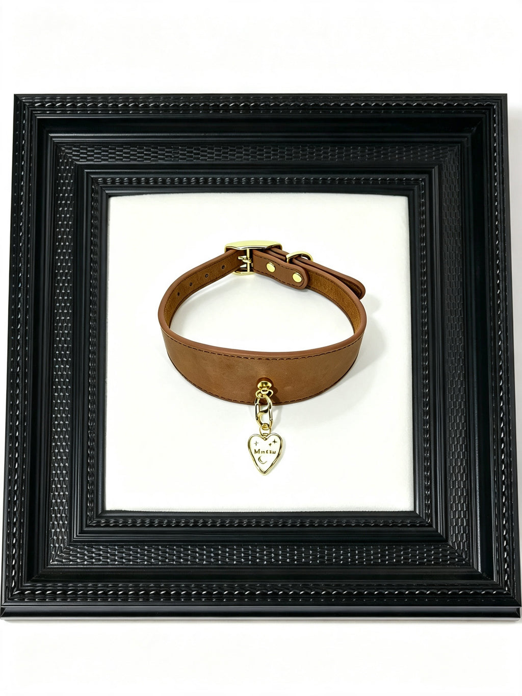 Faux Leather Pet Collar – brown collar displayed in black ornate picture frame with customizable Muttu heart charm pendant, luxury editorial product presentation. Pendant sold separately.